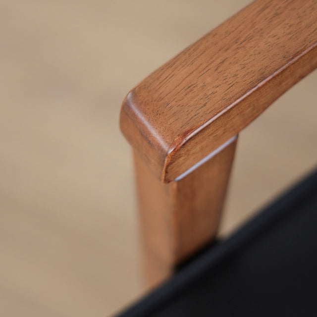 image rapprochée chaise noire avec assise rembourree et structure en bois naturel.