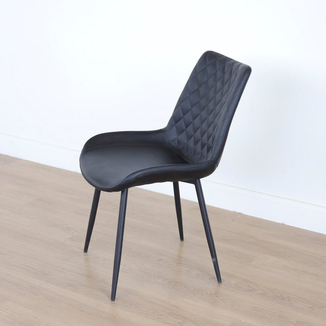 Chaise noire matelassee a dossier capitonne et pieds metal fins.