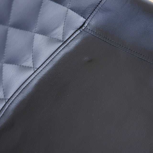 Chaise noire matelassee a dossier capitonne et pieds metal fins.