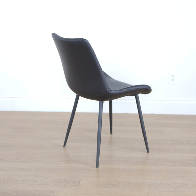 Chaise noire matelassee a dossier capitonne et pieds metal fins.