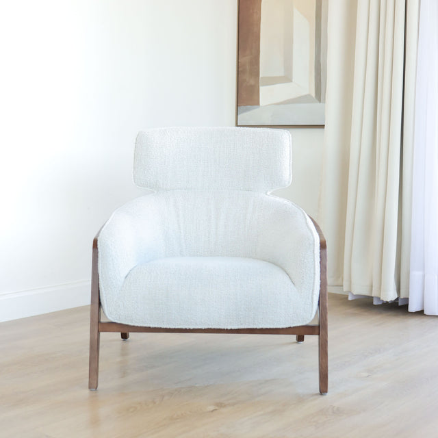 Fauteuil moderne en tissu bouclé ivoire avec structure en bois, idéal pour salon contemporain lumineux.