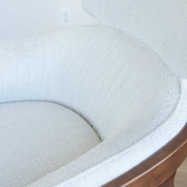 Fauteuil moderne en tissu bouclé ivoire avec structure en bois, idéal pour salon contemporain lumineux.