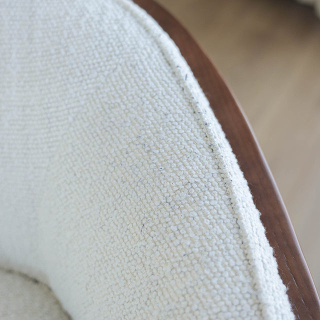 Fauteuil moderne en tissu bouclé ivoire avec structure en bois, idéal pour salon contemporain lumineux.