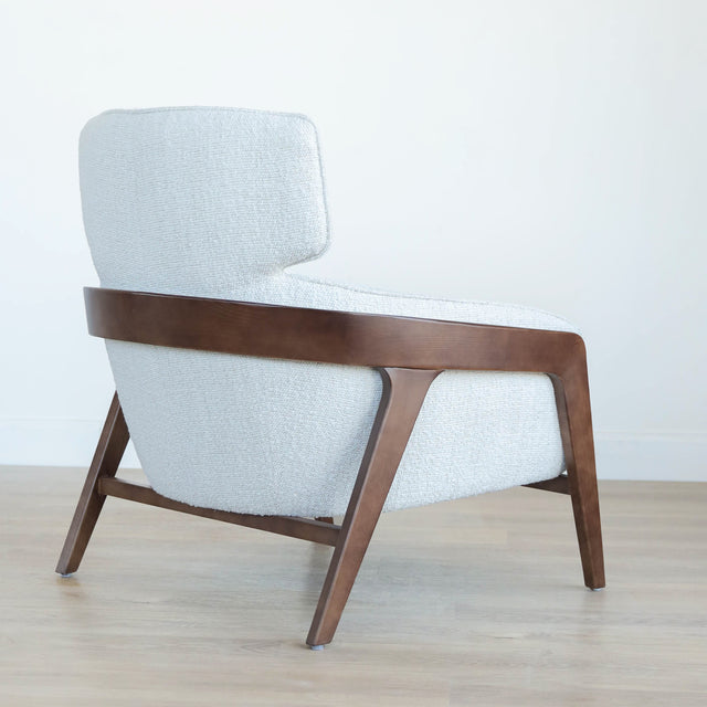 Fauteuil moderne en tissu bouclé ivoire avec structure en bois, idéal pour salon contemporain lumineux.