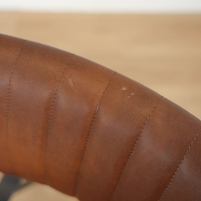 Deux chaises de salle à manger en cuir végane cognac, piètement métal noir, style industriel moderne.