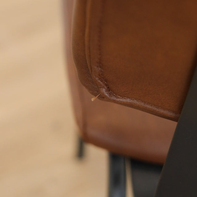 Deux chaises de salle à manger en cuir végane cognac, piètement métal noir, style industriel moderne.