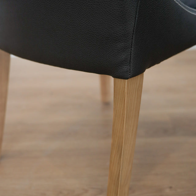 Lot de deux chaises de salle à manger en cuir végane noir avec pattes en bois pâle, design moderne et élégant.