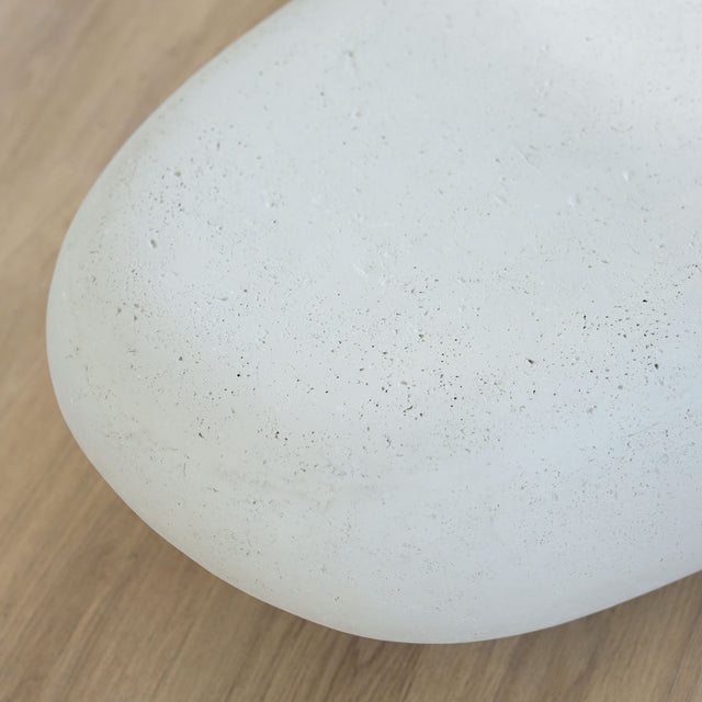 Table basse design en béton blanc, forme galet organique, idéale pour salon moderne et épuré.