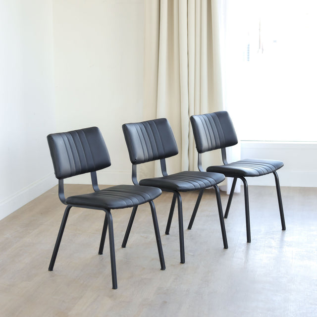 Lot de trois chaises de salle à manger noires en cuir végane noir avec piètement en métal noir, style moderne minimaliste.