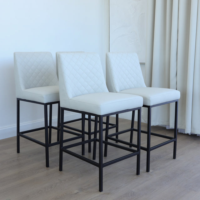 Lot de tabourets matelassés avec piétements noirs, style moderne.
