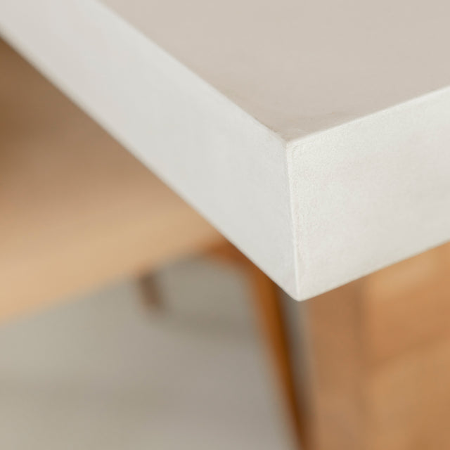 coin de table en beton blanc avec base en bois clair et finition lisse.