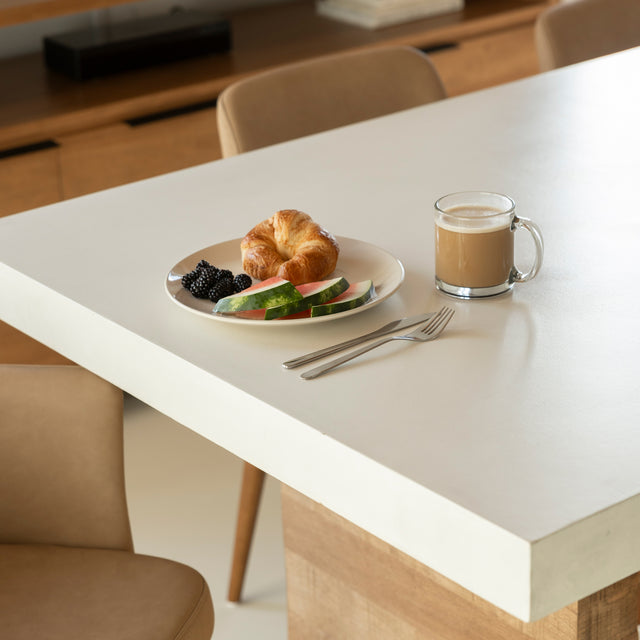 table en beton blanc avec base en bois clair et chaises beige elegantes.