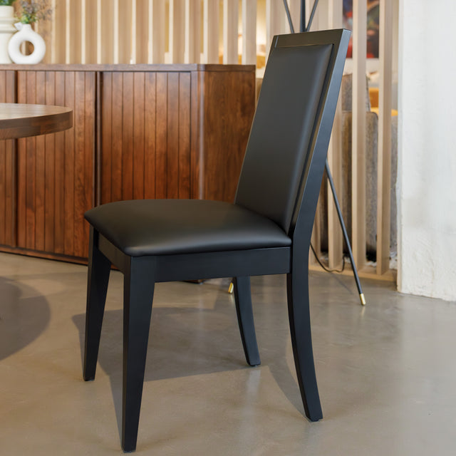 Chaise de salle à manger noire au design moderne avec assise rembourrée, dans un intérieur contemporain.