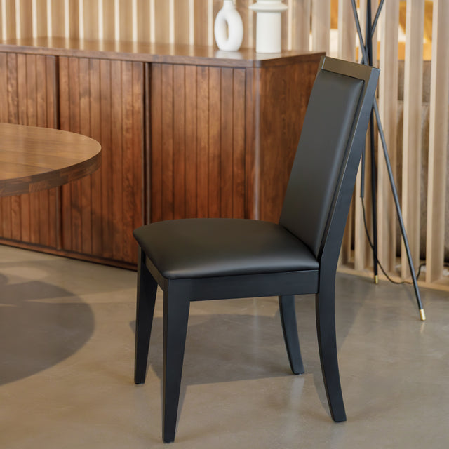Chaise de salle à manger noire au design moderne avec assise rembourrée, dans un intérieur contemporain.