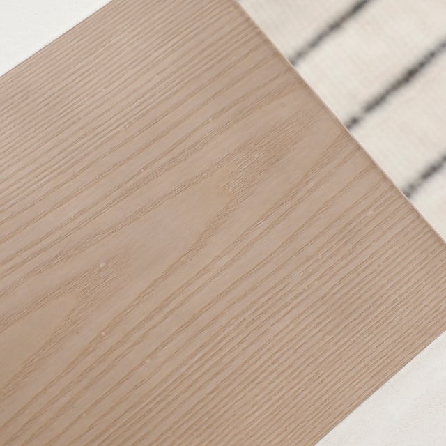 Gros plan sur insert en bois clair au centre du plateau de table blanche.