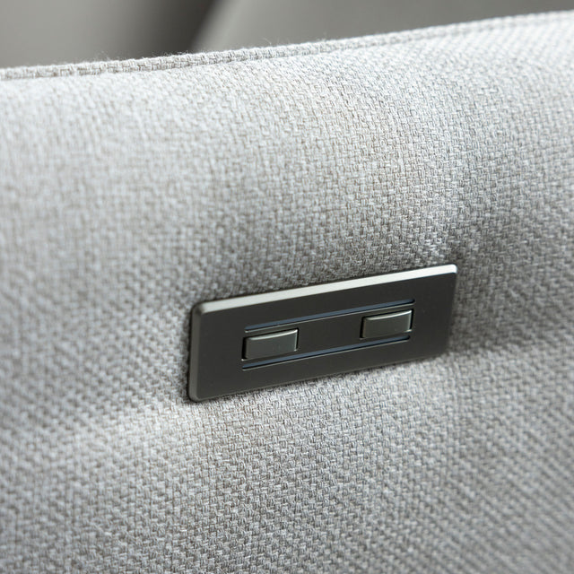 detail du bouton de commande metalique sur accoudoir de canape gris clair.