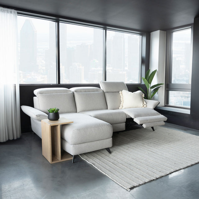 canape d angle gris clair avec tetiere et repose pieds reglables dans salon moderne.