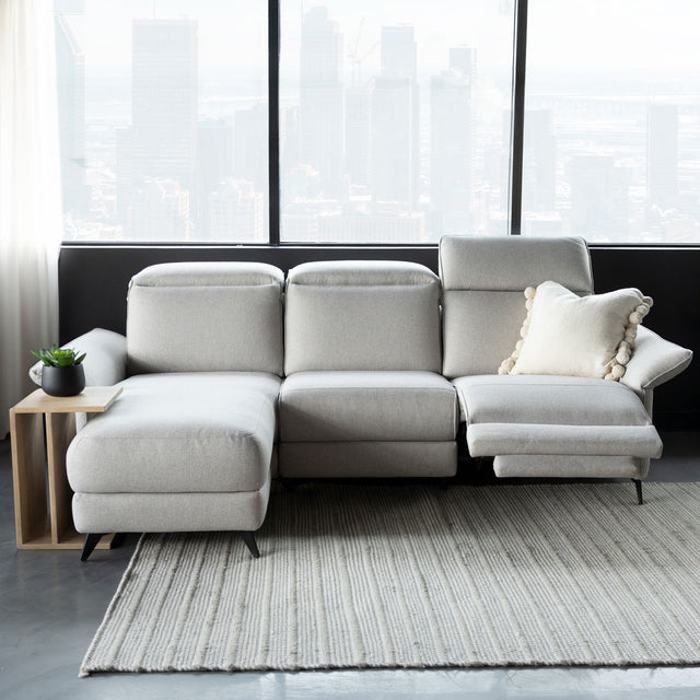 canape d angle gris clair avec tetiere et repose pieds reglables dans salon moderne.