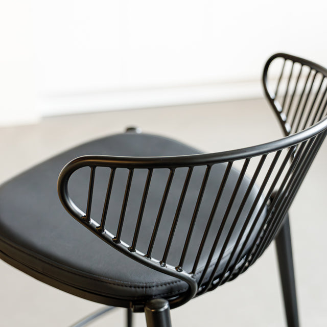 Tabouret de bar noir avec assise rembourrée et dossier ajouré design, idéal pour cuisine moderne.