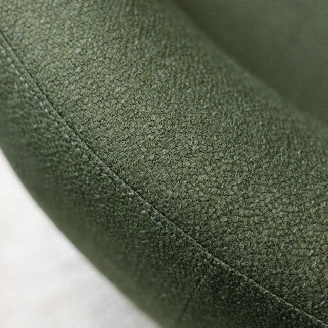 Fauteuil lounge vert en tissu bouclé avec base pivotante noire dans un salon moderne.