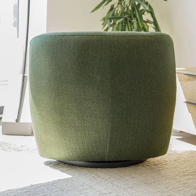 Fauteuil lounge vert en tissu bouclé avec base pivotante noire dans un salon moderne.