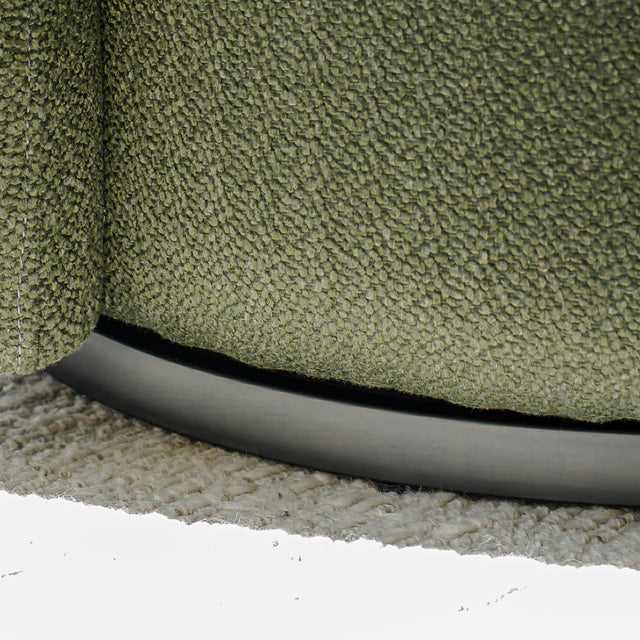 Fauteuil lounge vert en tissu bouclé avec base pivotante noire dans un salon moderne.