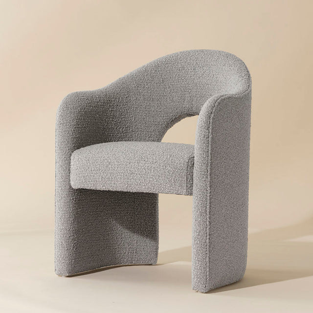 chaise grise en tissu boucle avec design courbe moderne et dossier enveloppant.