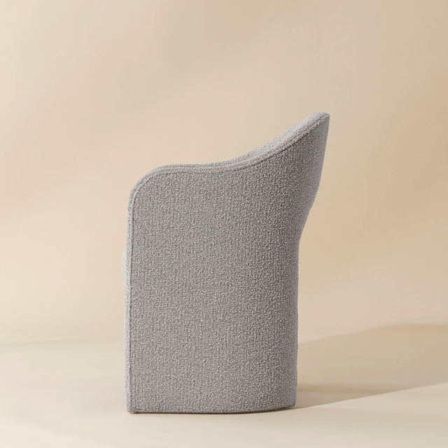 chaise grise en tissu boucle avec design courbe moderne et dossier enveloppant.