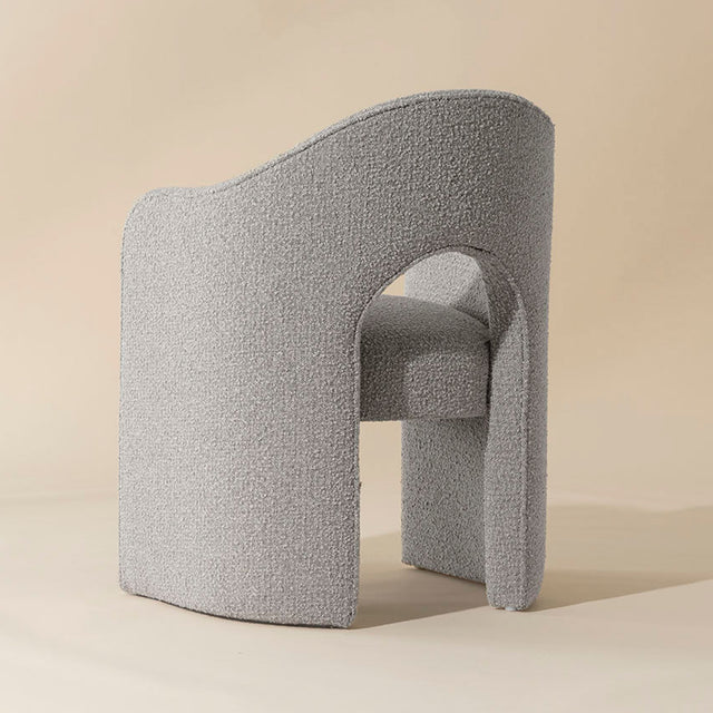 chaise grise en tissu boucle avec design courbe moderne et dossier enveloppant.