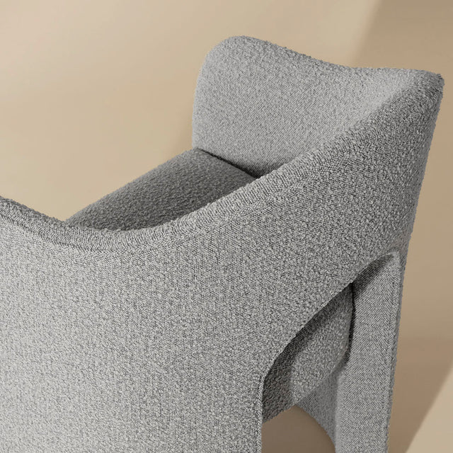chaise grise en tissu boucle avec design courbe moderne et dossier enveloppant.