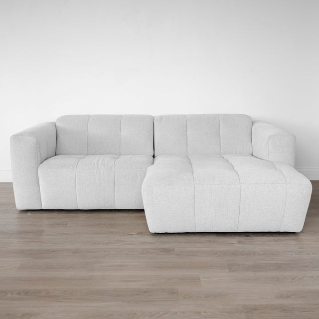 Canapé d’angle beige clair matelassé au style moderne et minimaliste.