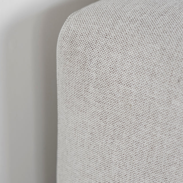 Gros plan sur le tissu texturé beige clair du canapé, montrant la finesse du tissage.