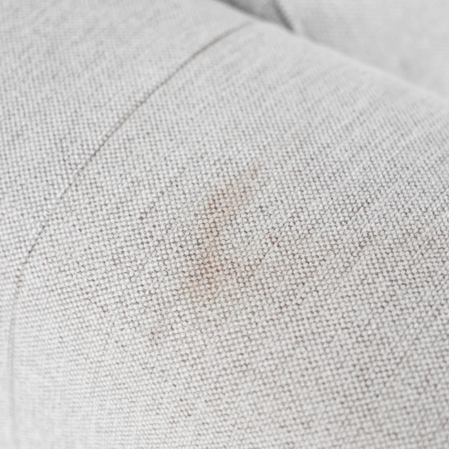 Gros plan sur le tissu texturé beige clair du canapé, montrant la finesse du tissage.