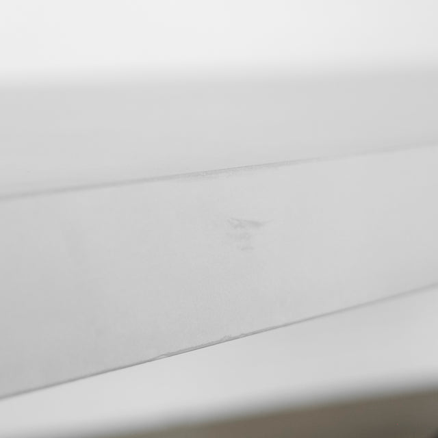 gros plan du bord d’un plateau de table blanc mat montrant une petite marque ou légère irrégularité sur la surface.