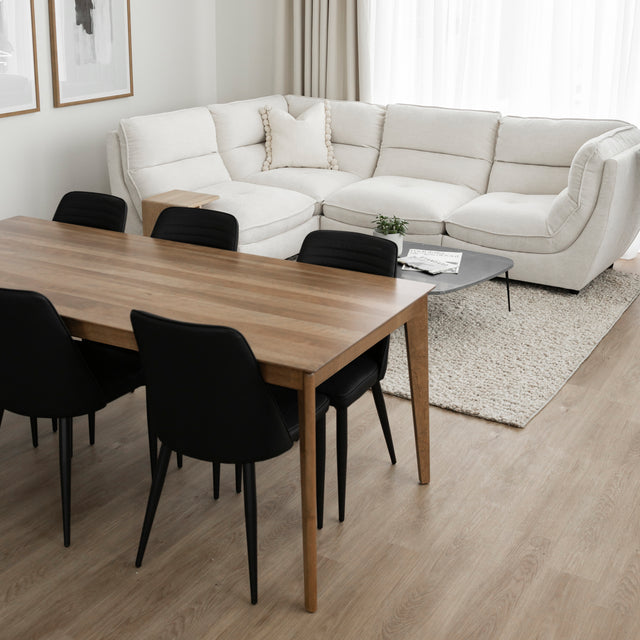 Table a manger en bois naturel avec six chaises noires dans salon moderne et lumineux.