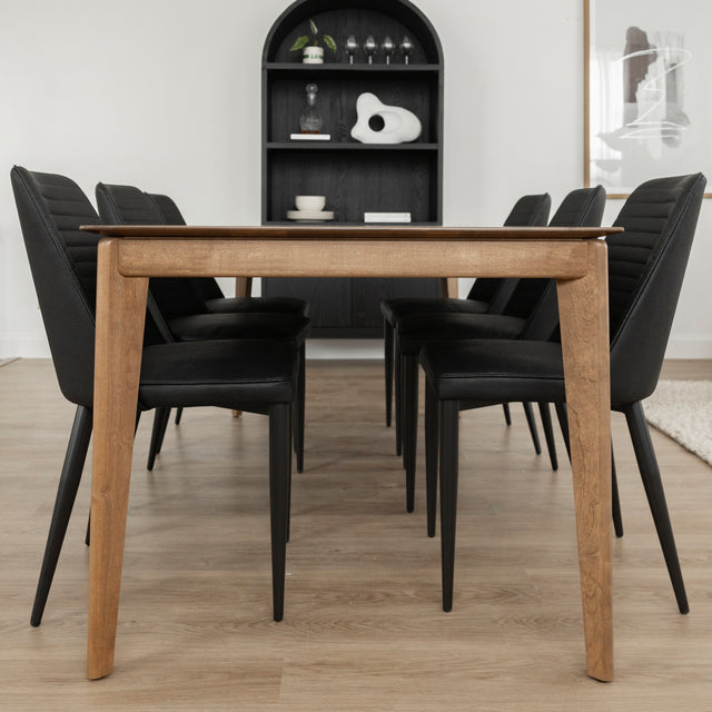 Table a manger en bois naturel avec six chaises noires dans salon moderne et lumineux.