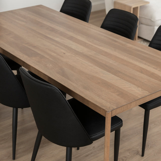 Table a manger en bois naturel avec six chaises noires dans salon moderne et lumineux.
