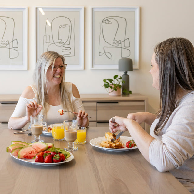 Petit dejeuner convivial sur table en bois clair avec fruits frais et jus dans decor moderne.