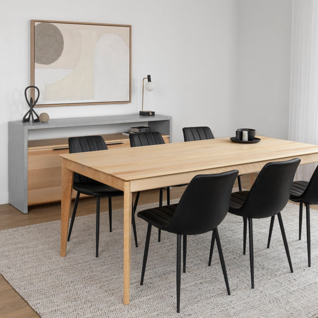 Table a manger en bois clair avec six chaises noires dans salle moderne et epuree.