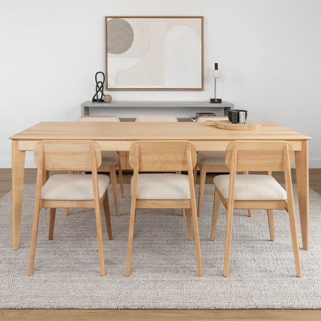 Table a manger en bois clair avec six chaises beiges dans une salle au style minimaliste.