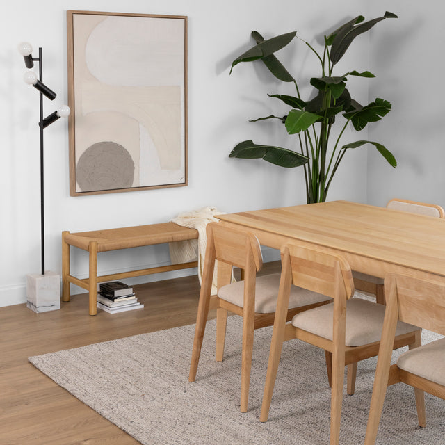 Table a manger en bois clair avec chaises beiges et banc assorti dans salle scandinave.