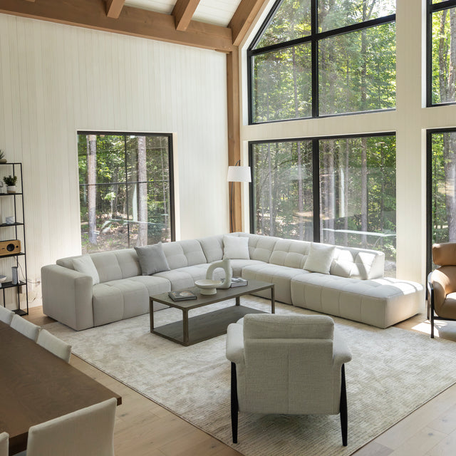 Grand salon moderne avec canape d angle beige, grande baie vitree et table basse en bois.