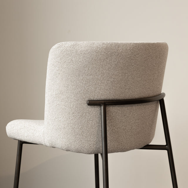 Tabouret de comptoir moderne en tissu beige avec piétement en métal noir, idéale pour cuisine ou îlot contemporain.