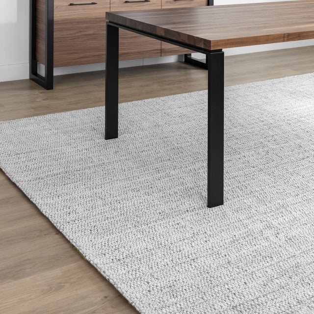 coin de table en bois avec pieds metalliques noirs sur grand tapis gris clair.