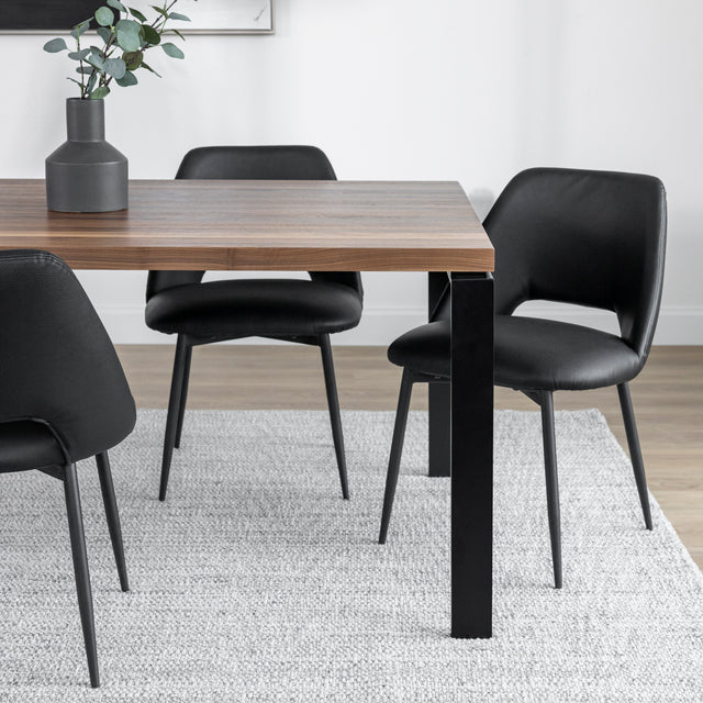 Salle a manger contemporaine avec table en bois et chaises noires sur tapis clair.