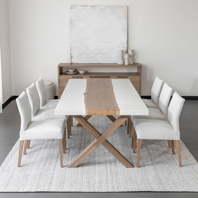 table de salle a manger moderne avec plateau en bois et resine blanche, pieds croises en bois clair et chaises beige sur tapis tissé clair.
