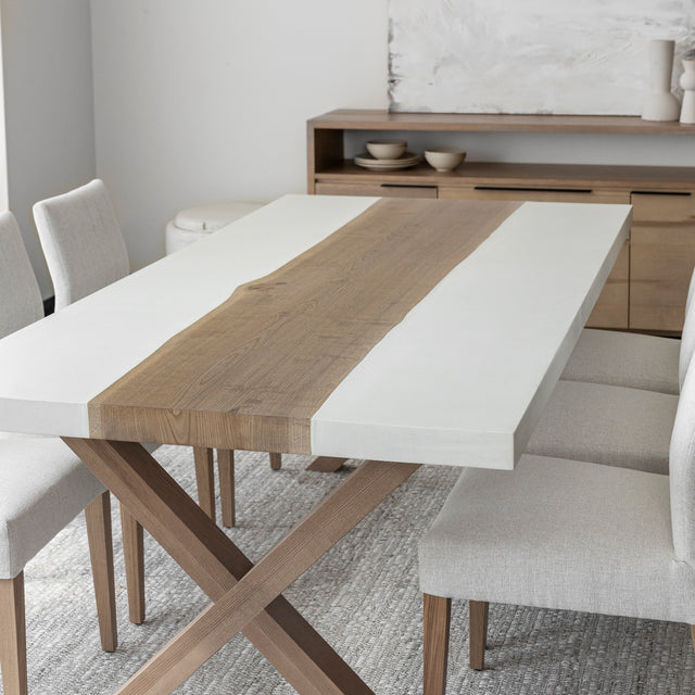 table de salle a manger moderne avec plateau en bois et resine blanche, pieds croises en bois clair et chaises beige sur tapis tissé clair.