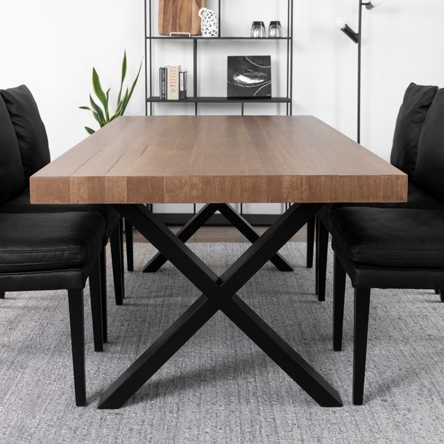 Table en bois massif avec pieds croises en metal noir et chaises noires modernes.