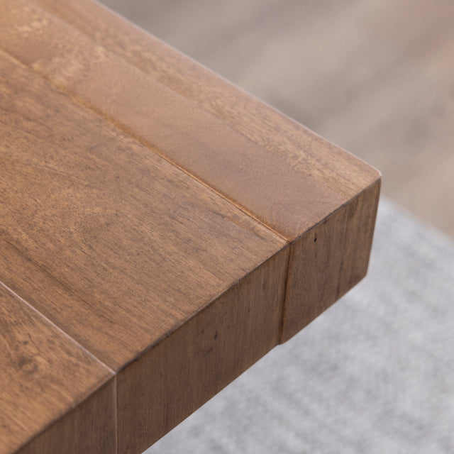 Gros plan sur angle de table en bois massif au fini lisse et naturel.