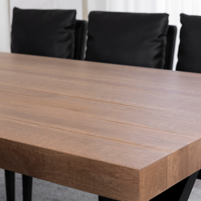 Table en bois massif au fini mat avec chaises noires contemporaines.